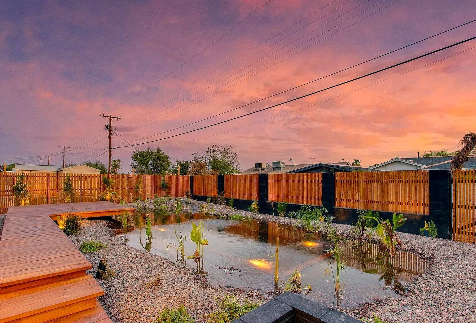 Cedar boardwalk and steps over a naturalized pond at dusk on a completed Coveted Contracting renovation.